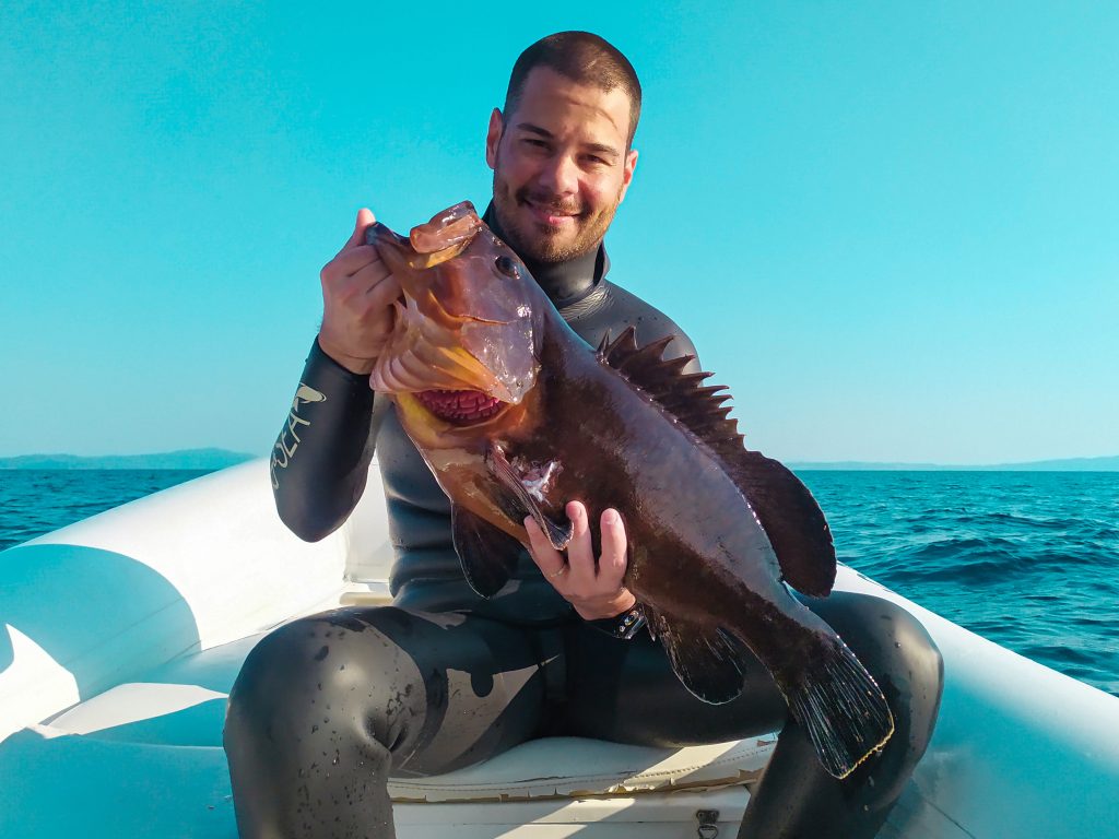 spearo holding a dusky grouper on the boat